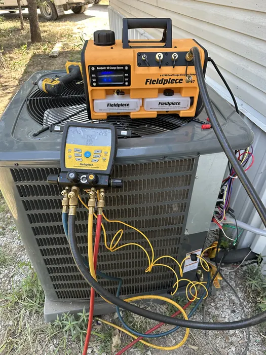 Vacuum pump and digital refrigerant gauges connected to an outdoor AC unit